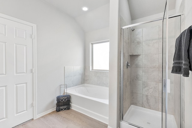 bathroom with lofted ceiling, hardwood / wood-style flooring, and plus walk in shower