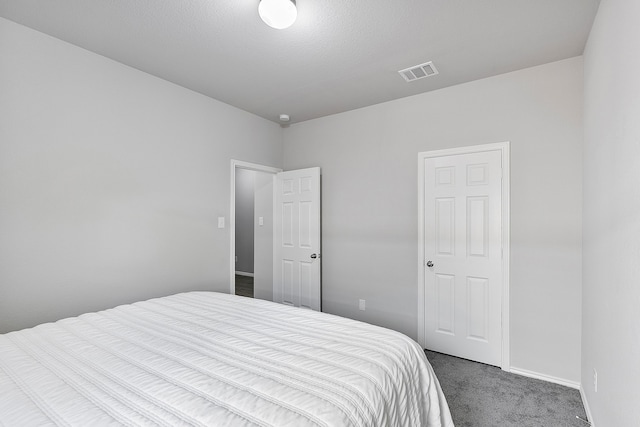 bedroom featuring a textured ceiling and dark carpet