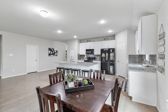 dining space with sink and light hardwood / wood-style flooring