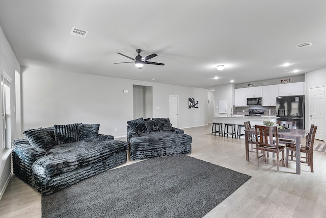 living room featuring sink, ceiling fan, and light hardwood / wood-style flooring