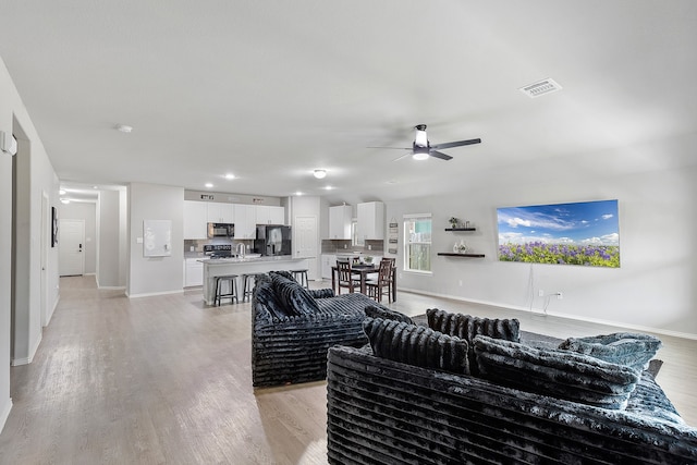 living room featuring light hardwood / wood-style flooring and ceiling fan