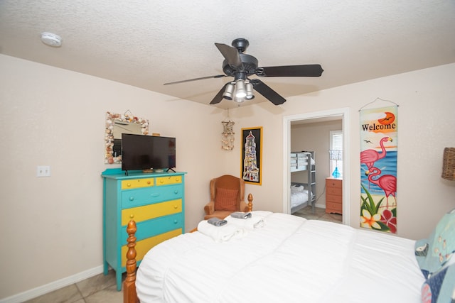 tiled bedroom with connected bathroom, a textured ceiling, and ceiling fan