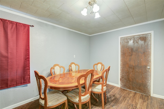 dining area featuring a notable chandelier, ornamental molding, and dark wood-type flooring