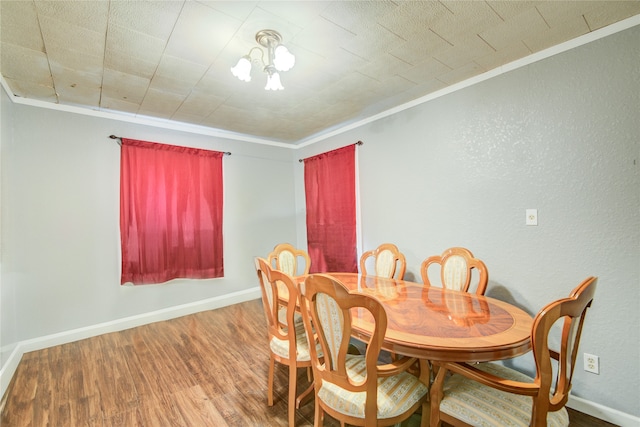 dining space with crown molding, hardwood / wood-style flooring, and an inviting chandelier