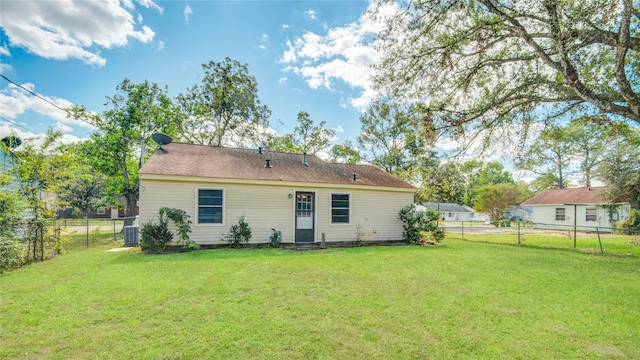 back of house with cooling unit and a lawn