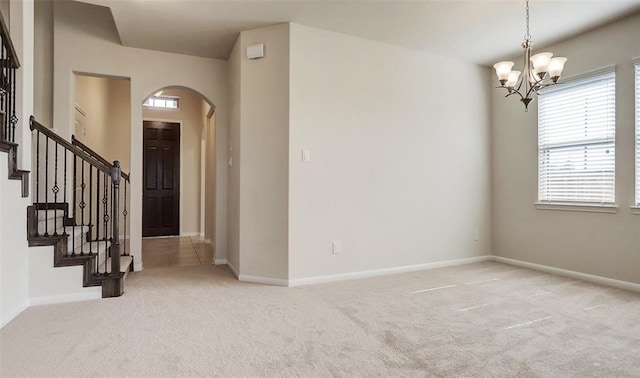 empty room featuring light carpet and a chandelier