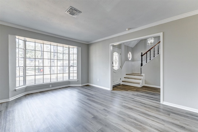 interior space with an inviting chandelier, light hardwood / wood-style flooring, ornamental molding, and a textured ceiling