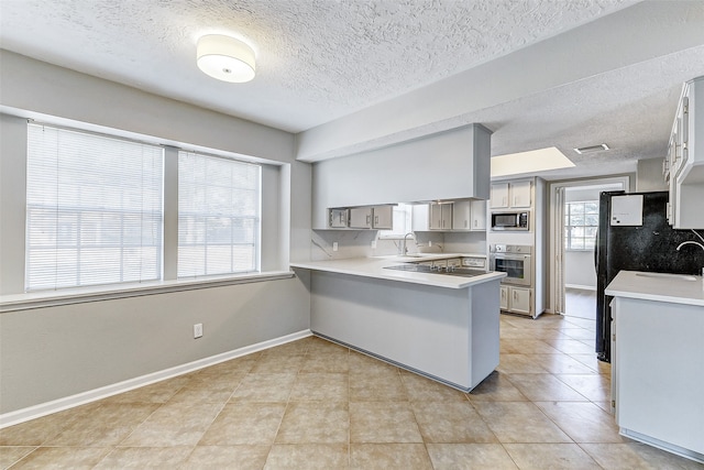 kitchen with plenty of natural light, stainless steel oven, kitchen peninsula, and built in microwave