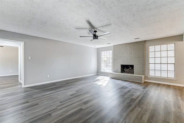 unfurnished living room featuring ceiling fan, a fireplace, a textured ceiling, and dark hardwood / wood-style floors