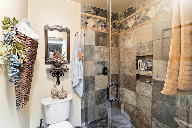 bathroom featuring a shower with door and toilet