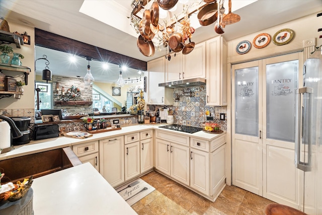 kitchen featuring black electric stovetop, tasteful backsplash, cream cabinets, and hanging light fixtures