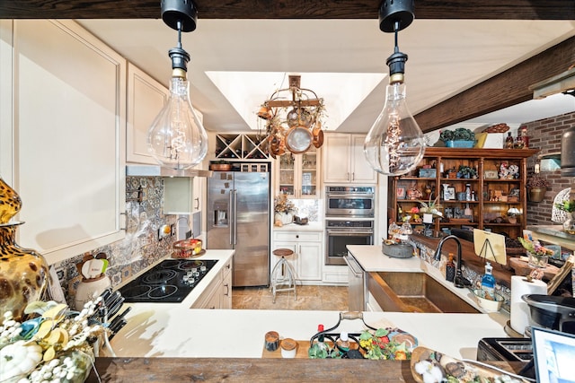 kitchen featuring brick wall, appliances with stainless steel finishes, sink, and decorative light fixtures