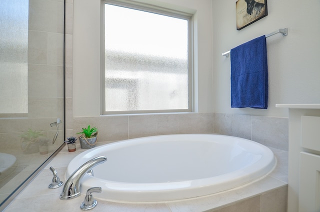 bathroom featuring a relaxing tiled tub and a wealth of natural light