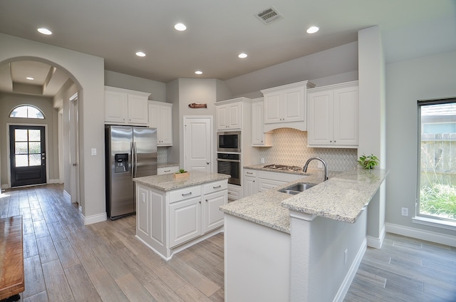 kitchen with sink, kitchen peninsula, stainless steel appliances, and a healthy amount of sunlight