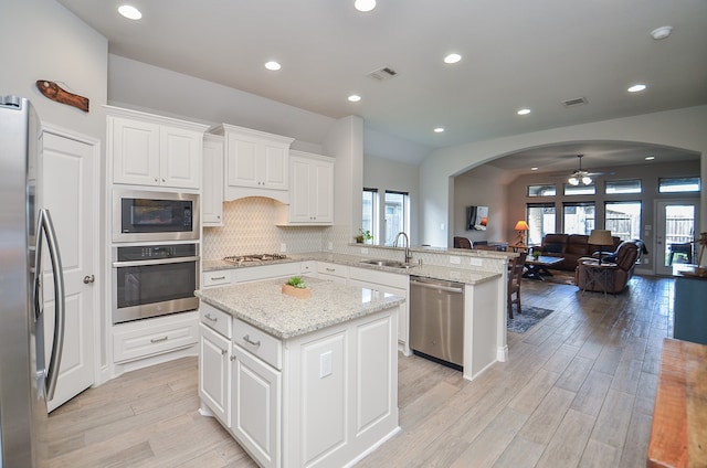 kitchen featuring light wood-type flooring, stainless steel appliances, plenty of natural light, and a kitchen island