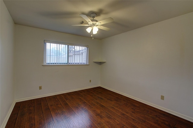 spare room featuring dark wood finished floors, a ceiling fan, and baseboards