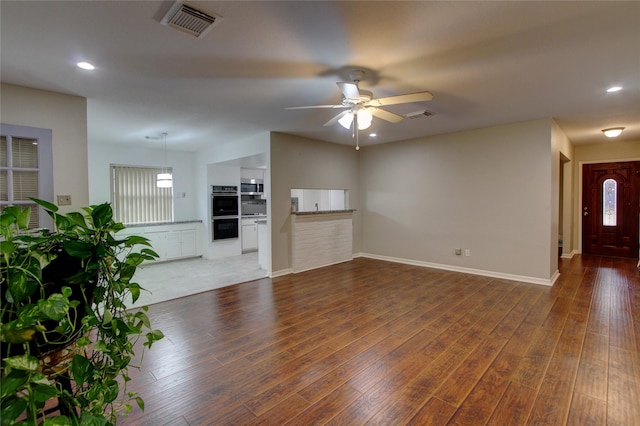 unfurnished living room featuring ceiling fan, visible vents, baseboards, and wood finished floors