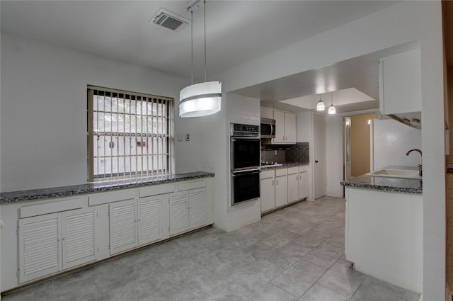 kitchen featuring white appliances, visible vents, a sink, white cabinets, and tasteful backsplash