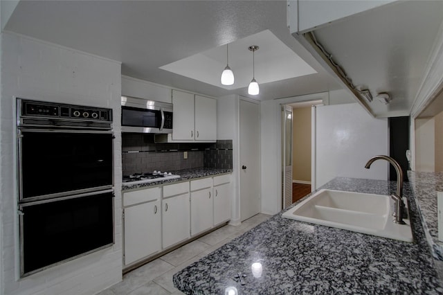 kitchen with dobule oven black, a sink, stainless steel microwave, white cabinets, and white gas stovetop