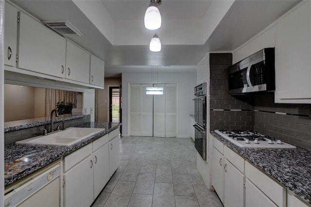 kitchen featuring visible vents, a sink, a tray ceiling, tasteful backsplash, and white appliances