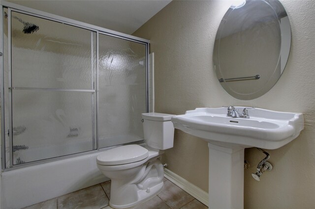 full bath featuring tile patterned floors, toilet, baseboards, and shower / bath combination with glass door