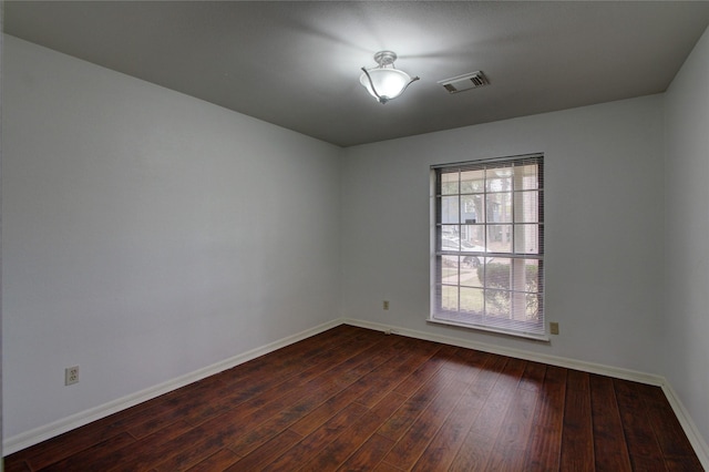 empty room with visible vents, baseboards, and dark wood-style floors