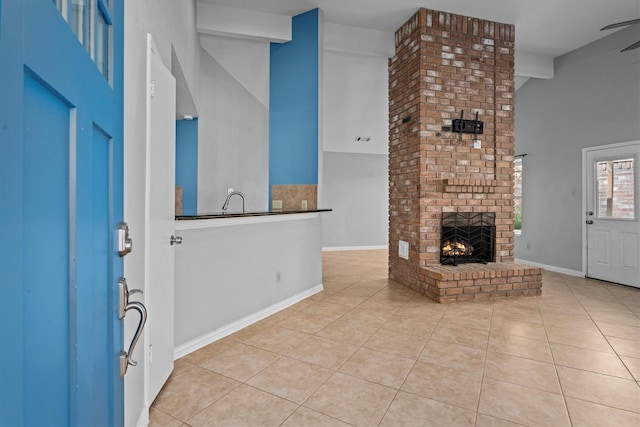 unfurnished living room with ceiling fan, light tile patterned flooring, lofted ceiling, and a brick fireplace