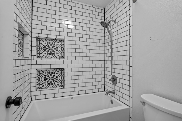 bathroom with tiled shower / bath combo and toilet