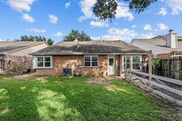 rear view of house with central AC unit and a yard