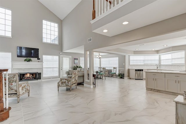 living room featuring sink, an inviting chandelier, a wealth of natural light, and a high ceiling