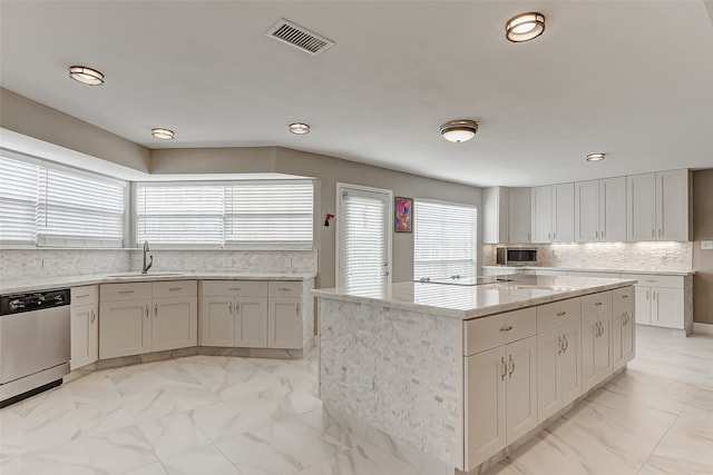 kitchen with decorative backsplash, white cabinetry, stainless steel appliances, sink, and a center island