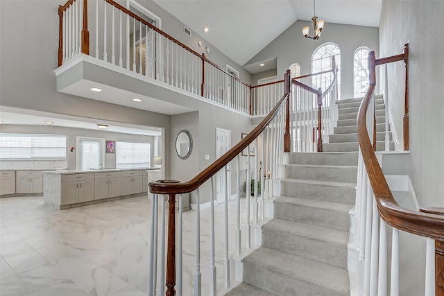 staircase with a chandelier and high vaulted ceiling