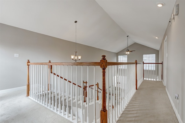 hallway with light carpet, lofted ceiling, and a chandelier