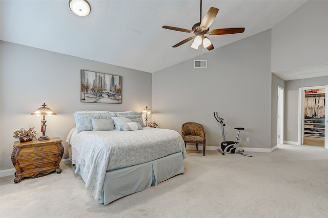 carpeted bedroom featuring a closet, ceiling fan, a walk in closet, and vaulted ceiling