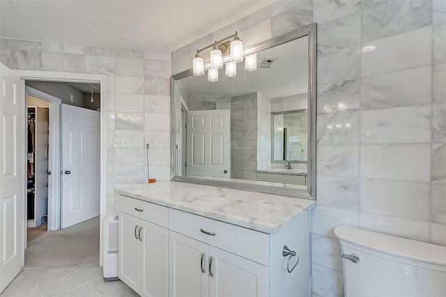 bathroom featuring vanity, tile walls, toilet, and walk in shower