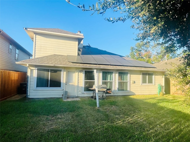 rear view of property with solar panels and a yard