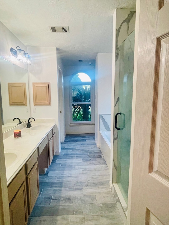 bathroom featuring vanity, a textured ceiling, independent shower and bath, and wood-type flooring