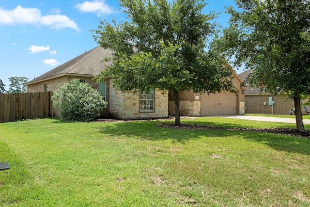 view of property hidden behind natural elements featuring a garage and a front lawn