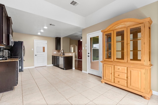 kitchen featuring light stone counters, dark brown cabinets, light tile patterned flooring, and appliances with stainless steel finishes