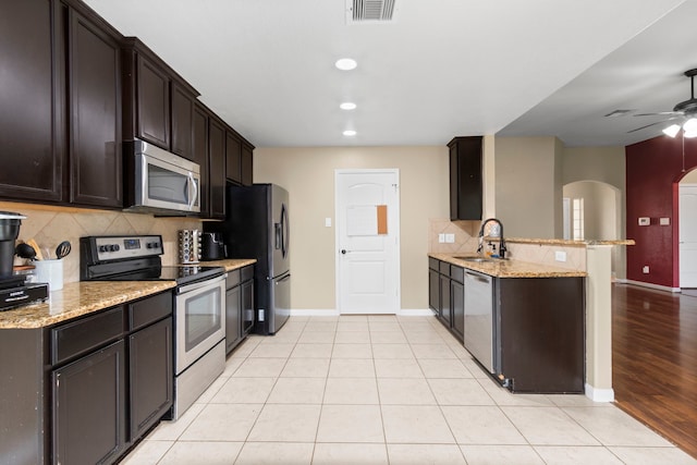 kitchen with light stone counters, sink, kitchen peninsula, and stainless steel appliances