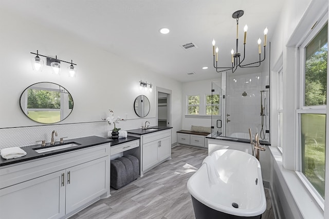 bathroom featuring backsplash, independent shower and bath, hardwood / wood-style floors, vanity, and a chandelier