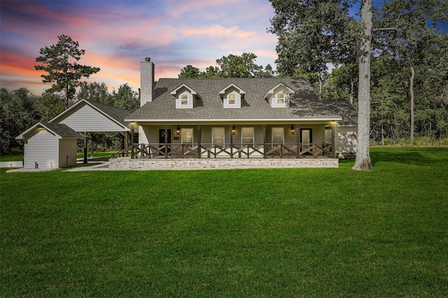 view of front of property with covered porch, a storage unit, and a lawn