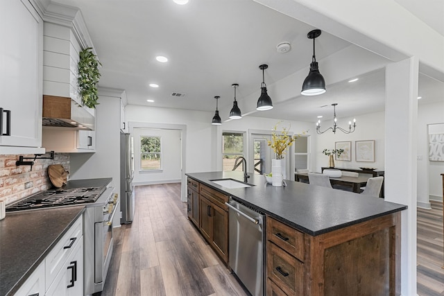 kitchen featuring a kitchen island with sink, dark hardwood / wood-style floors, stainless steel appliances, decorative light fixtures, and white cabinetry