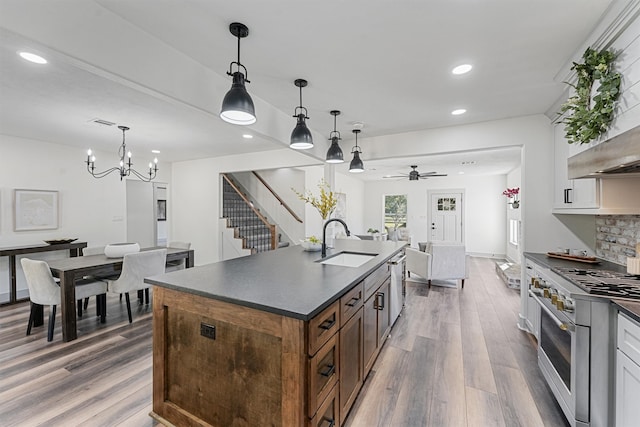 kitchen featuring white cabinets, hanging light fixtures, appliances with stainless steel finishes, wood-type flooring, and sink