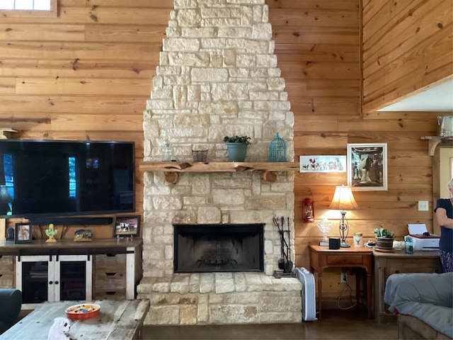 unfurnished living room with wood walls, a stone fireplace, and concrete flooring