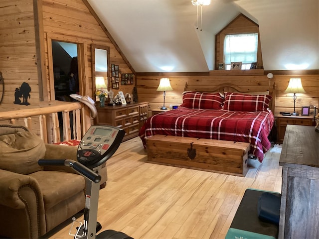 bedroom featuring wooden walls, light hardwood / wood-style flooring, and lofted ceiling