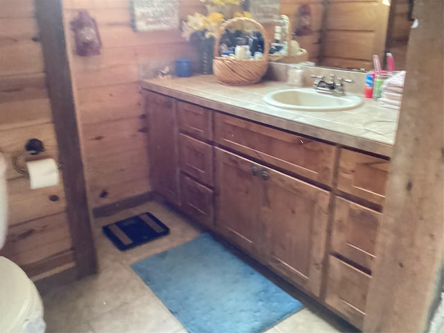 bathroom featuring tile patterned flooring, vanity, toilet, and wood walls