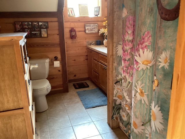 bathroom with tile patterned floors, wooden walls, vanity, and toilet