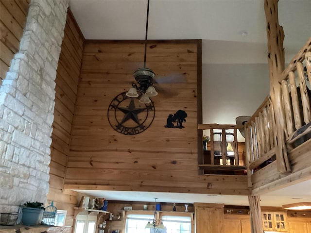 interior details featuring ceiling fan and wooden walls