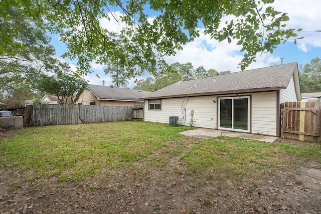 rear view of property with central AC unit, a yard, and a patio area